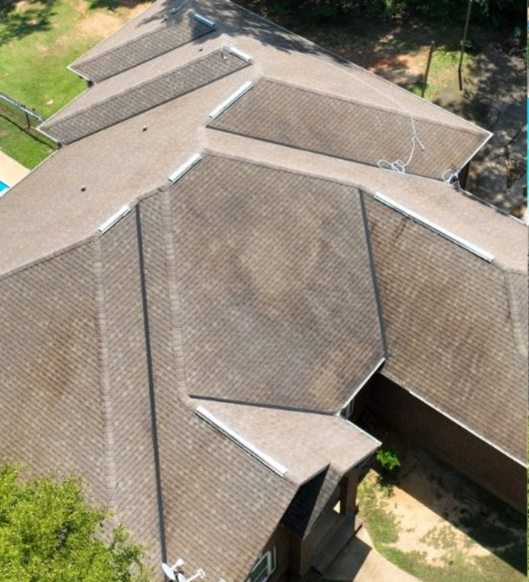Aerial view of a large, multi-section house with brown tiled roof and skylights.