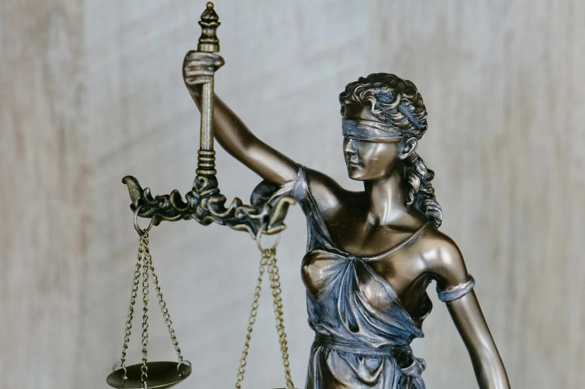 A statue of Lady Justice holding a set of scales in her left hand, with a blindfold over her eyes, symbolizing impartiality and fairness in the justice system.