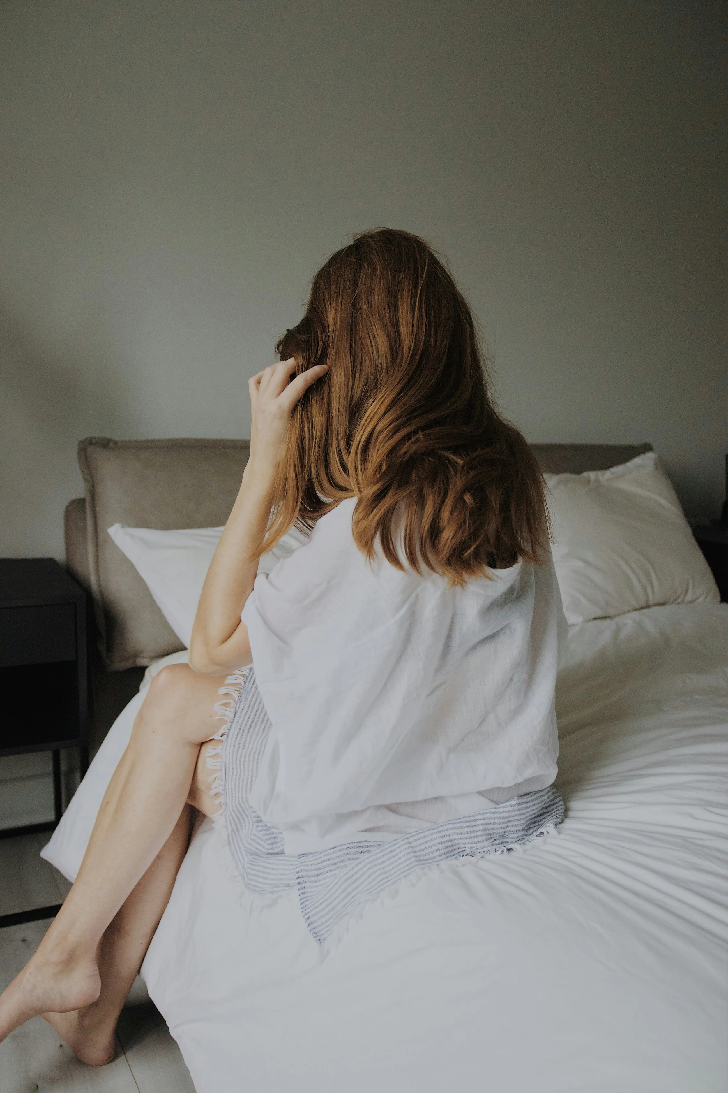 A woman sitting on a bed, preparing for a lymphatic session in Ontario