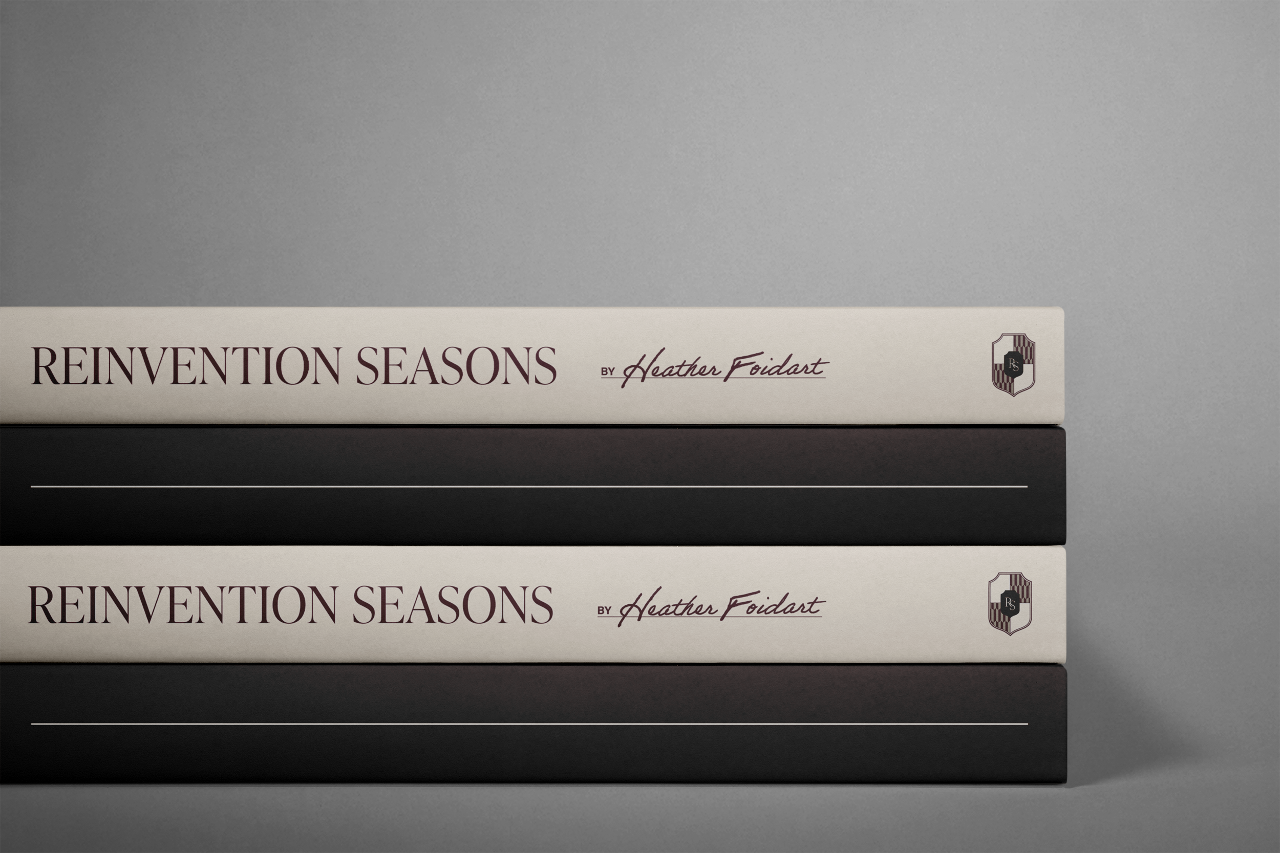 Stacked books with titles "Reinvention Seasons" by Heather Foidart on top, with a shield logo on the side, set against a gray background.