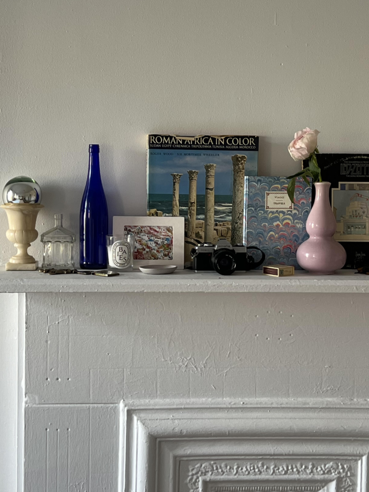 layered, styled shelf with antique and vintage vases, books, and art