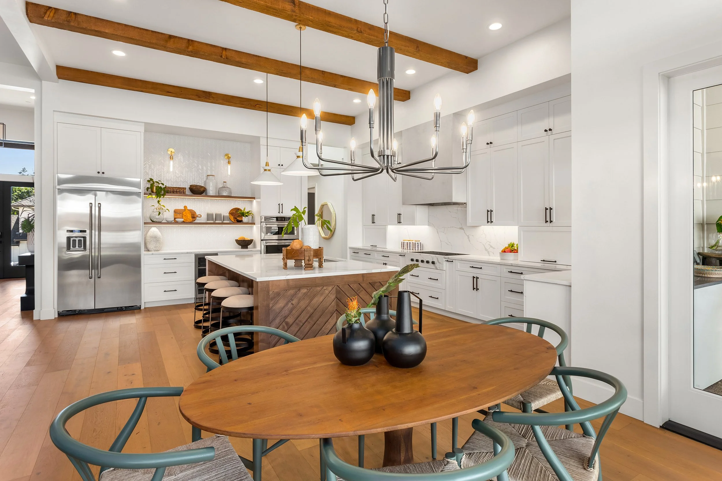 Luxury home kitchen and dining area featuring a large center island, stainless steel appliances, pendant lighting, hardwood floors, and an open-concept interior design