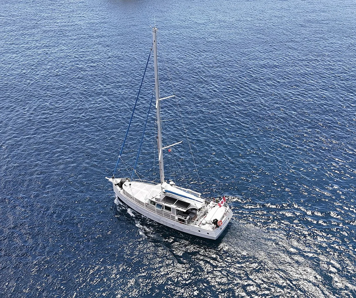Un voilier blanc naviguant sur une mer bleue vastes et calmes, vue aérienne
