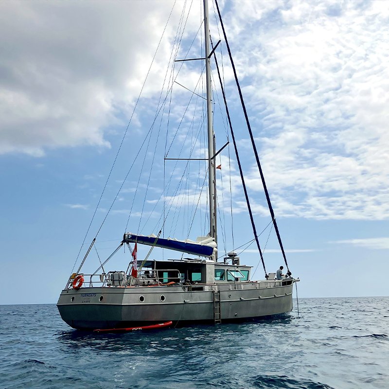 Un voilier en mer sous un ciel partiellement nuageux.
