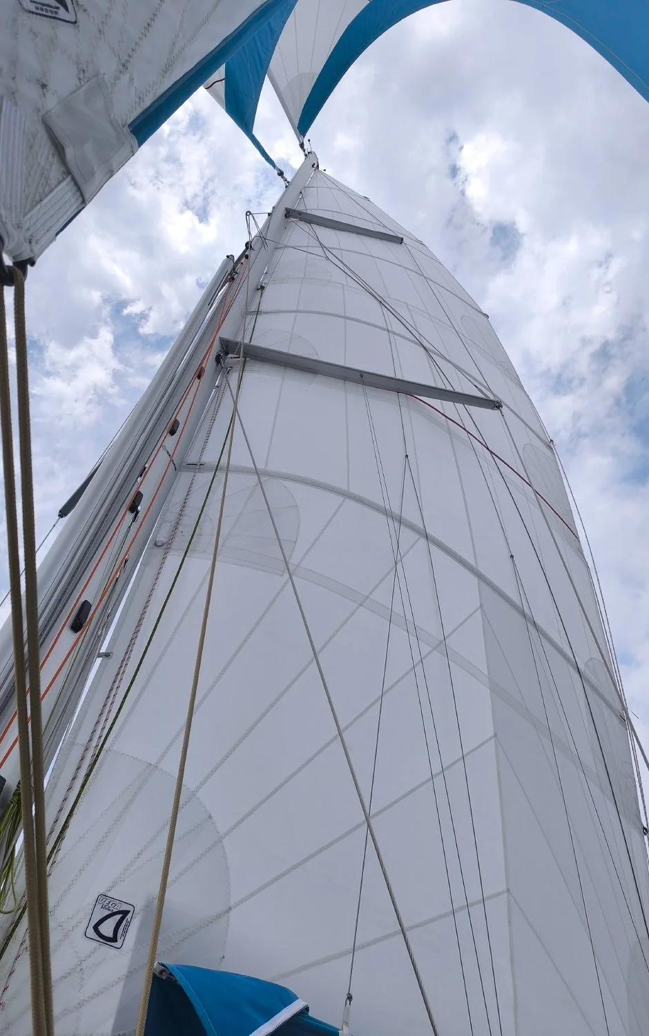 Vue du mât et des voiles d'un bateau à voile, le ciel avec des nuages en arrière-plan.