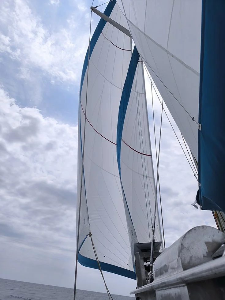 Voile de bateau gonflée sous un ciel nuageux, vue de dessous et côté