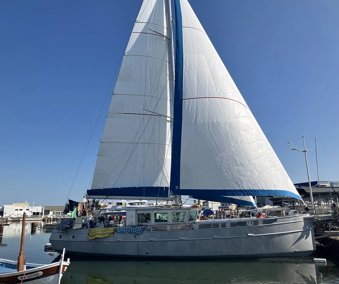 Bateau à voiles stationné dans un port sous un ciel ensoleillé.
