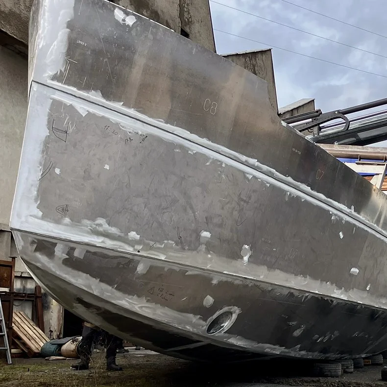 Une coque de bateau en construction en métal dans un atelier, vue de dessous.