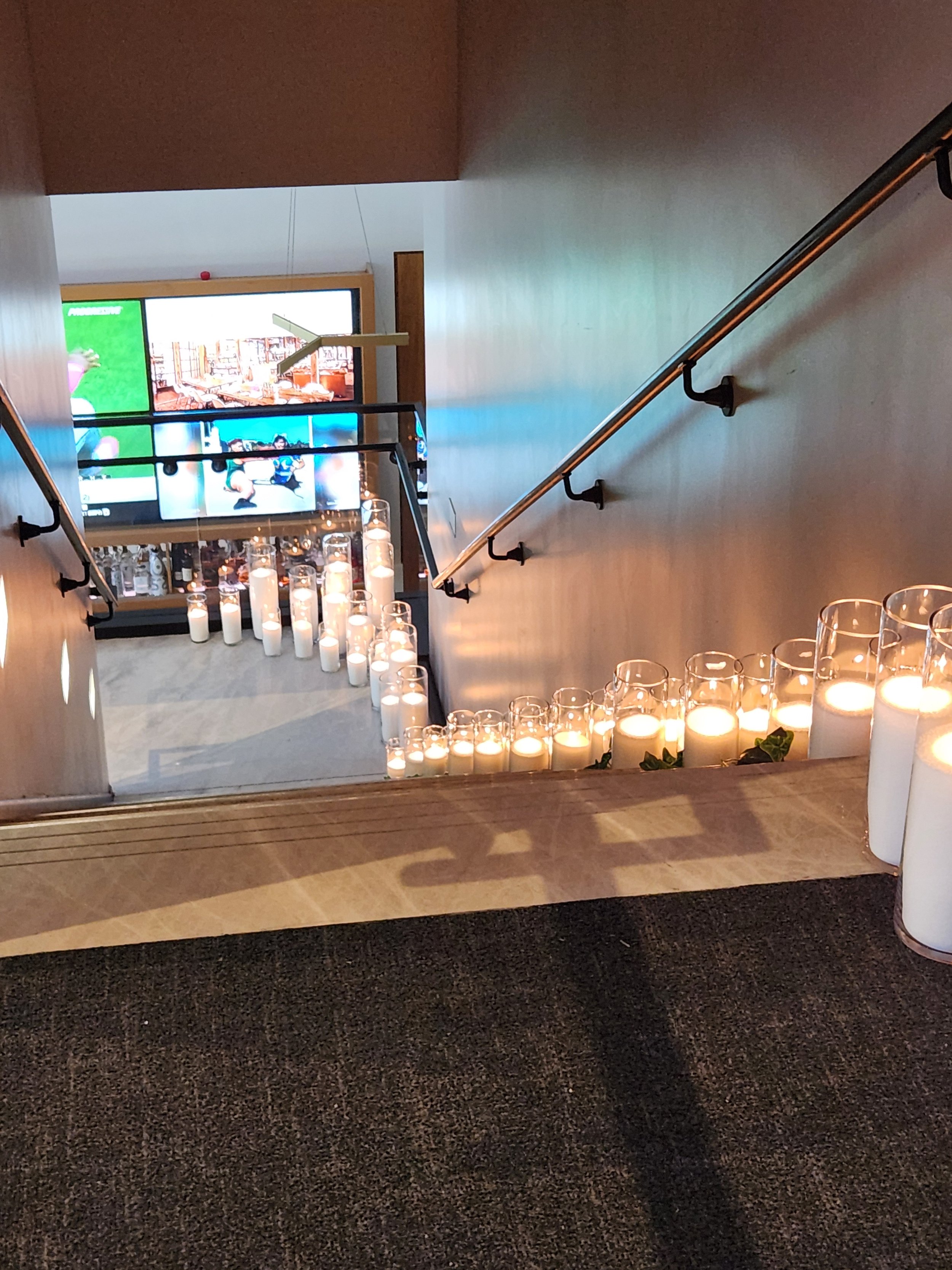 Large-scale event candle installation with glowing pearl wax candles in clear glass vessels lining both sides of a staircase for an elegant Columbus, Ohio event