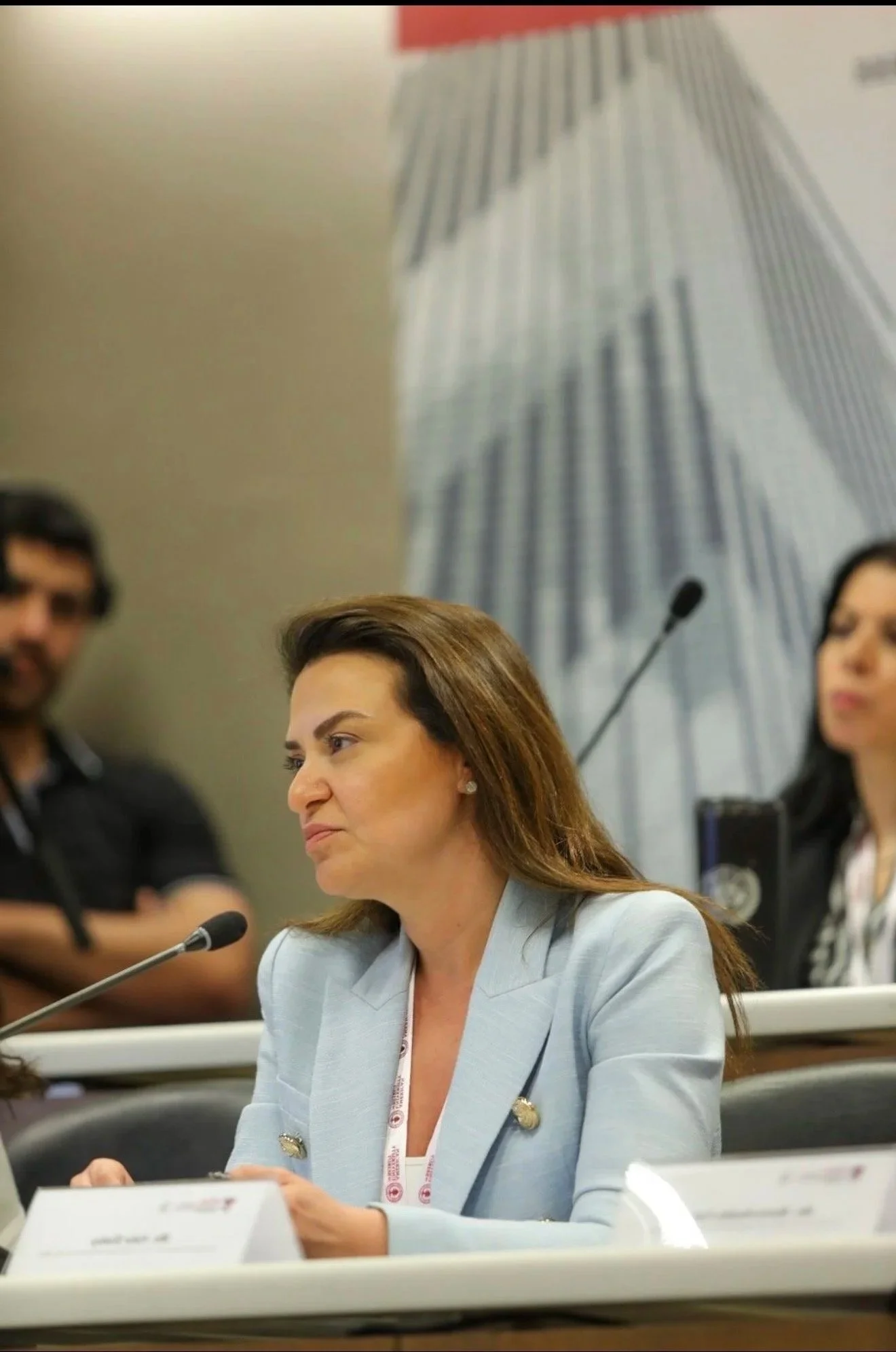 Hala Achkar Slaibi, from People & Co,, sitting at a table with a microphone in front of her during a conference or hearing.