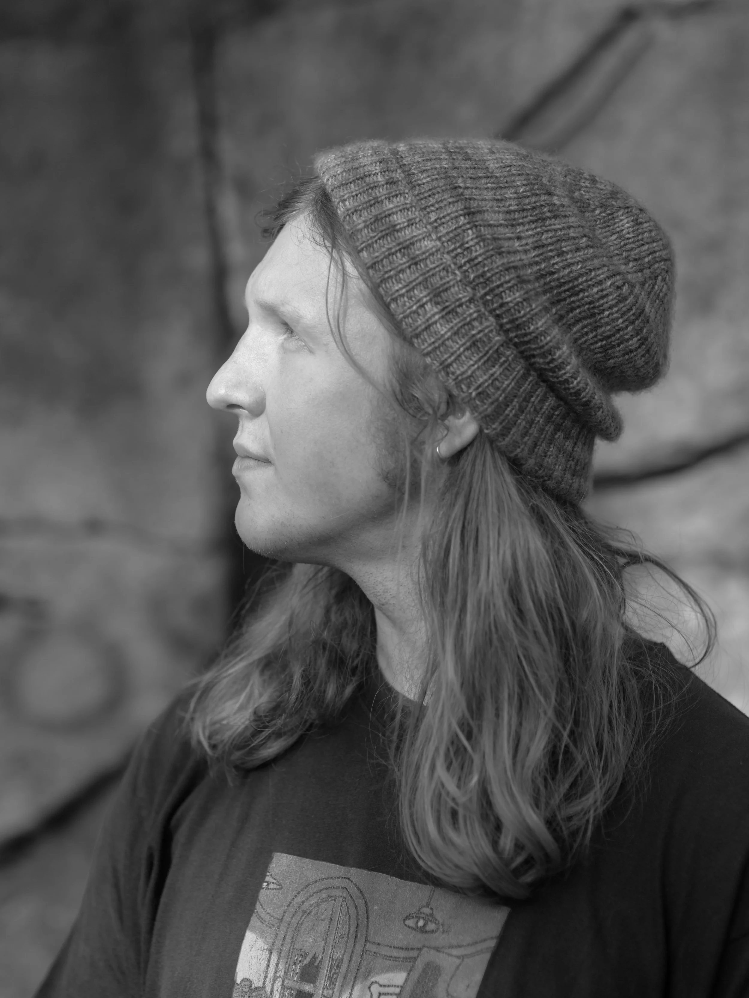 Side profile of a person wearing a knit beanie and a graphic T-shirt.