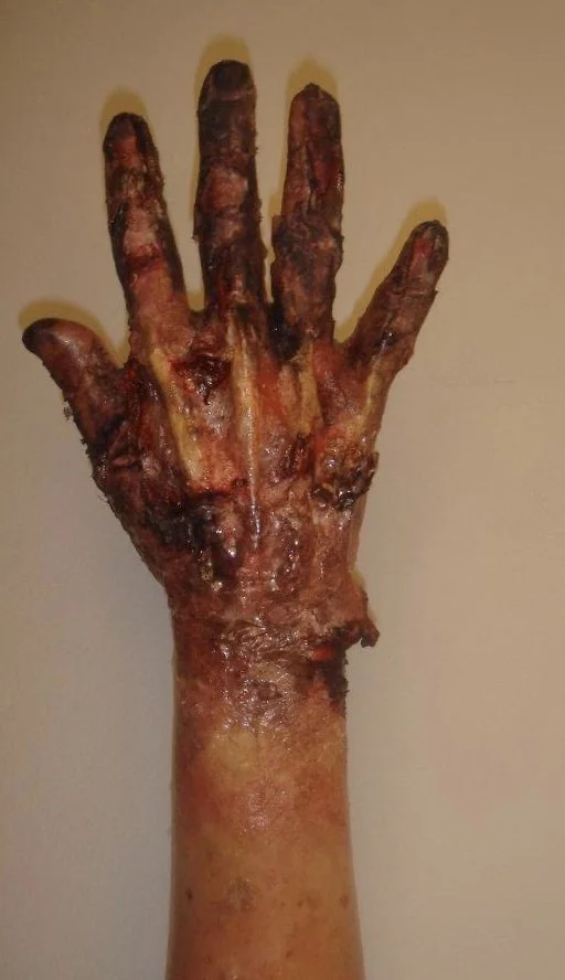 A cooked, roasted hand resembling a human hand with fingers extended, against a plain background.
