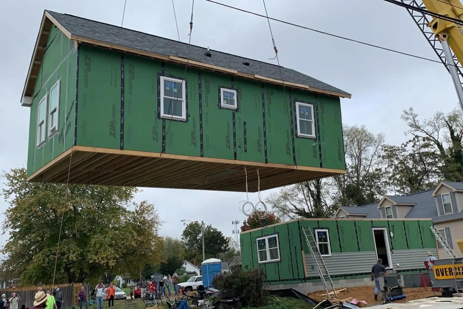 House under construction in the air held up by a crane