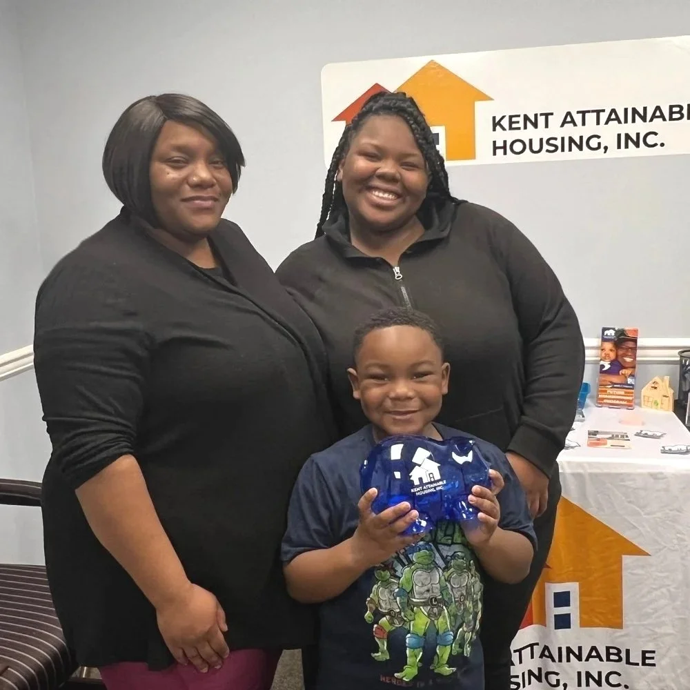 Two women and small boy holding a piggy bank