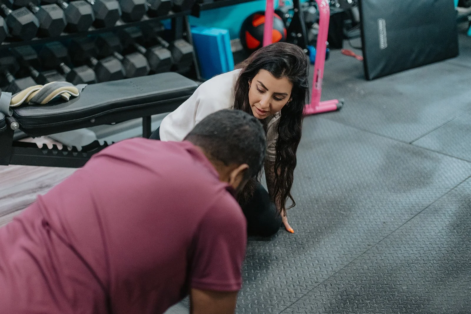 A woman and a man are doing push-ups together on the gym floor.