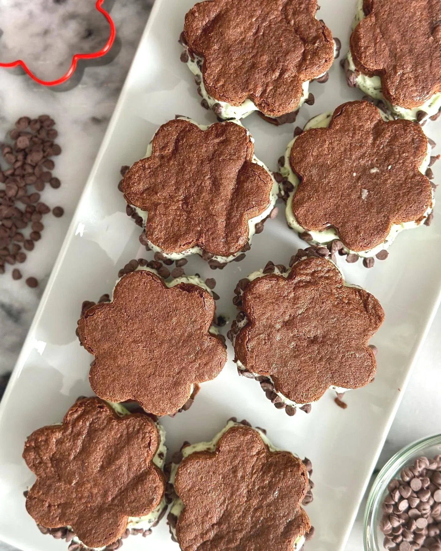 A white rectangular platter with several heart-shaped cookies topped with chocolate cookies.