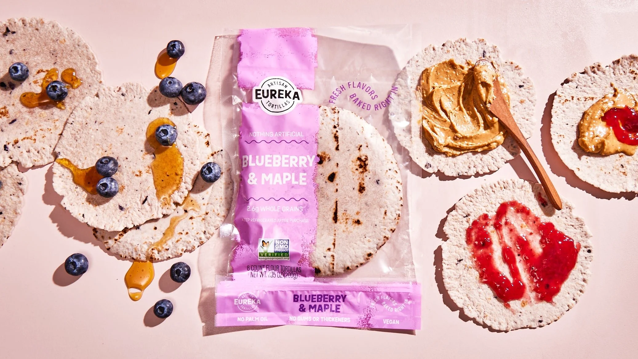 Unsalted flour tortillas topped with blueberries, peanut butter, and various fruit preserves, arranged on a flat surface.