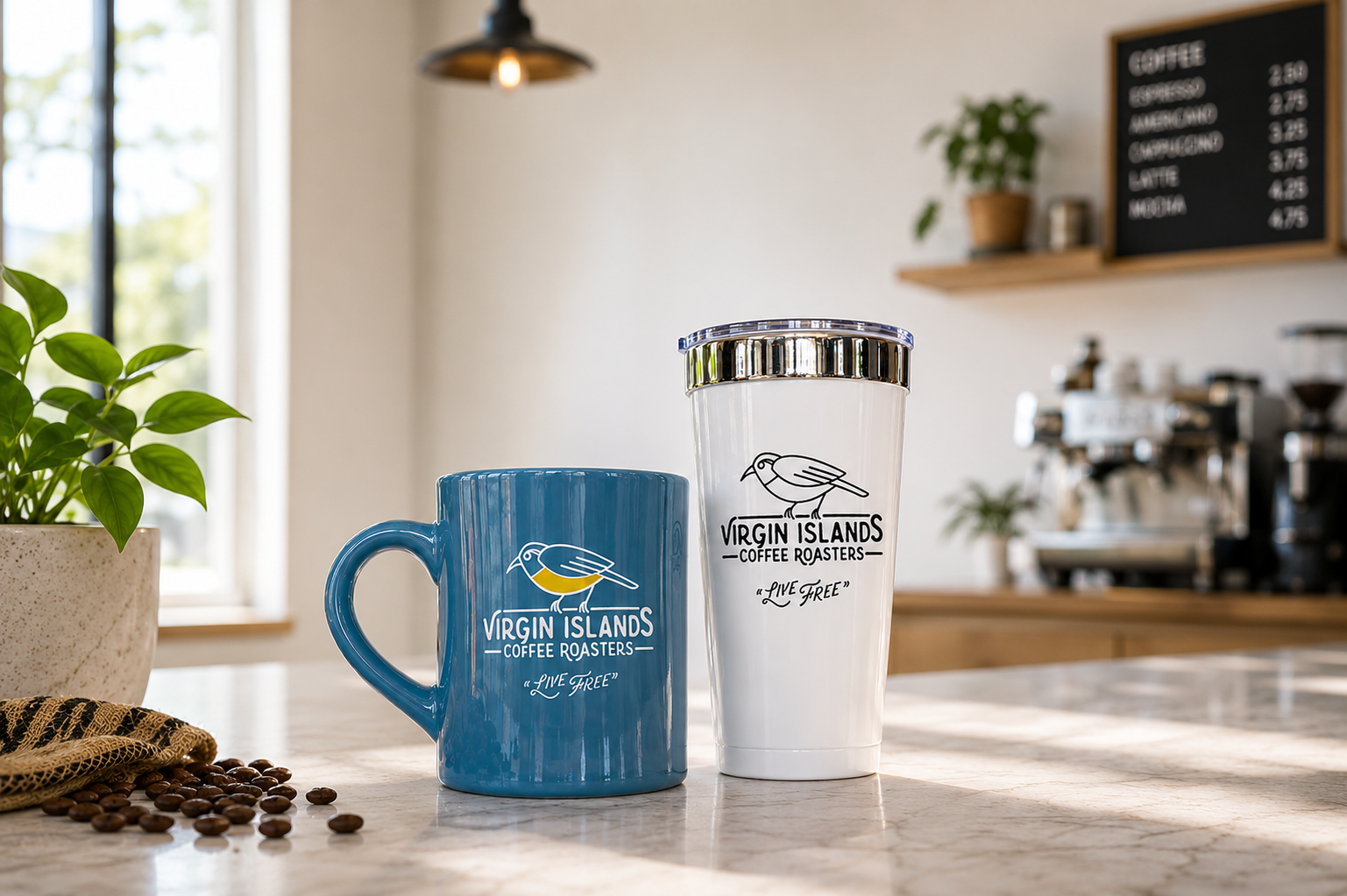 A blue mug and a white travel tumbler with the Virgin Islands Coffee Roasters logo on a countertop in a coffee shop. There are coffee beans and a potted plant nearby, with a menu board and coffee equipment in the background.