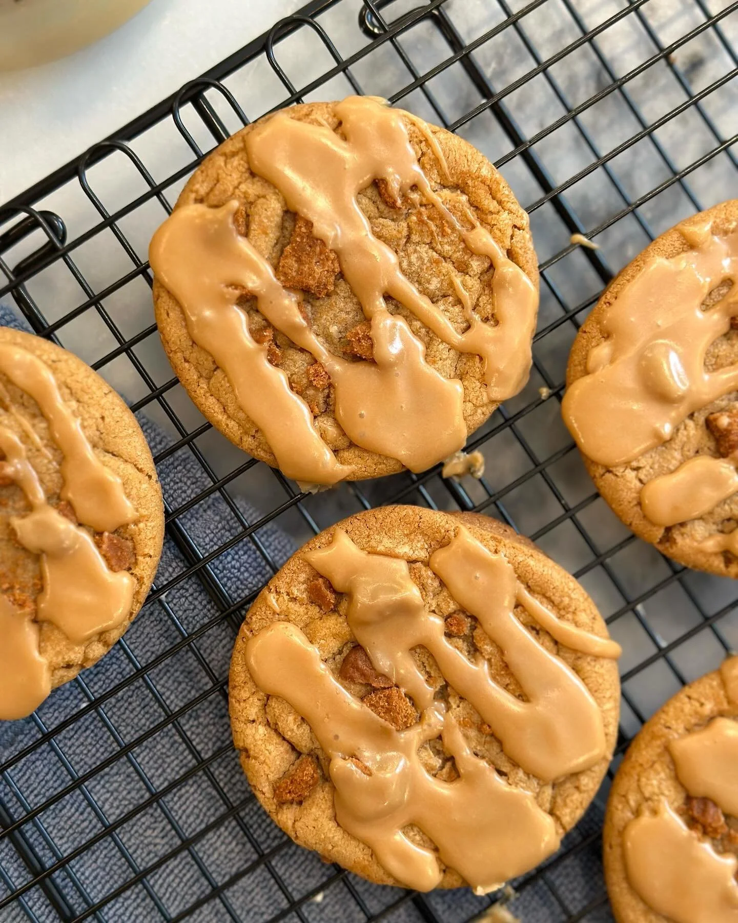 Close-up of freshly baked cookies with caramel drizzle on a cooling rack.