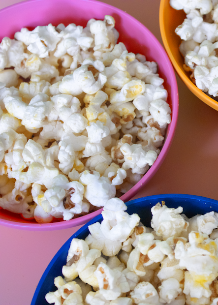 Balloons of popcorn in pink, orange, and blue bowls.