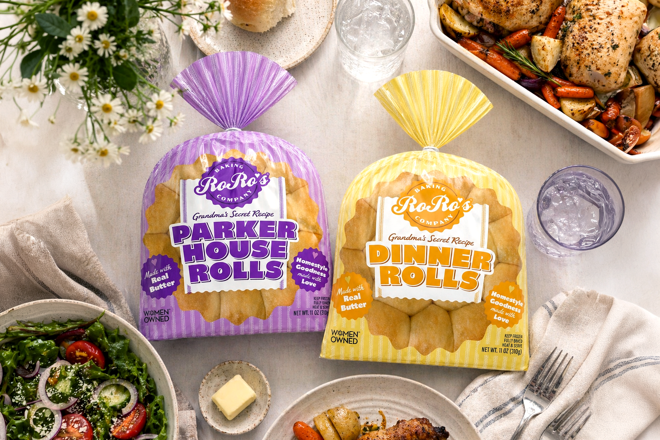 Two packages of RoRo's brand dinner rolls, one purple labeled 'Parker House Rolls' and one yellow labeled 'Dinner Rolls', on a dinner table with side dishes and a glass of water.