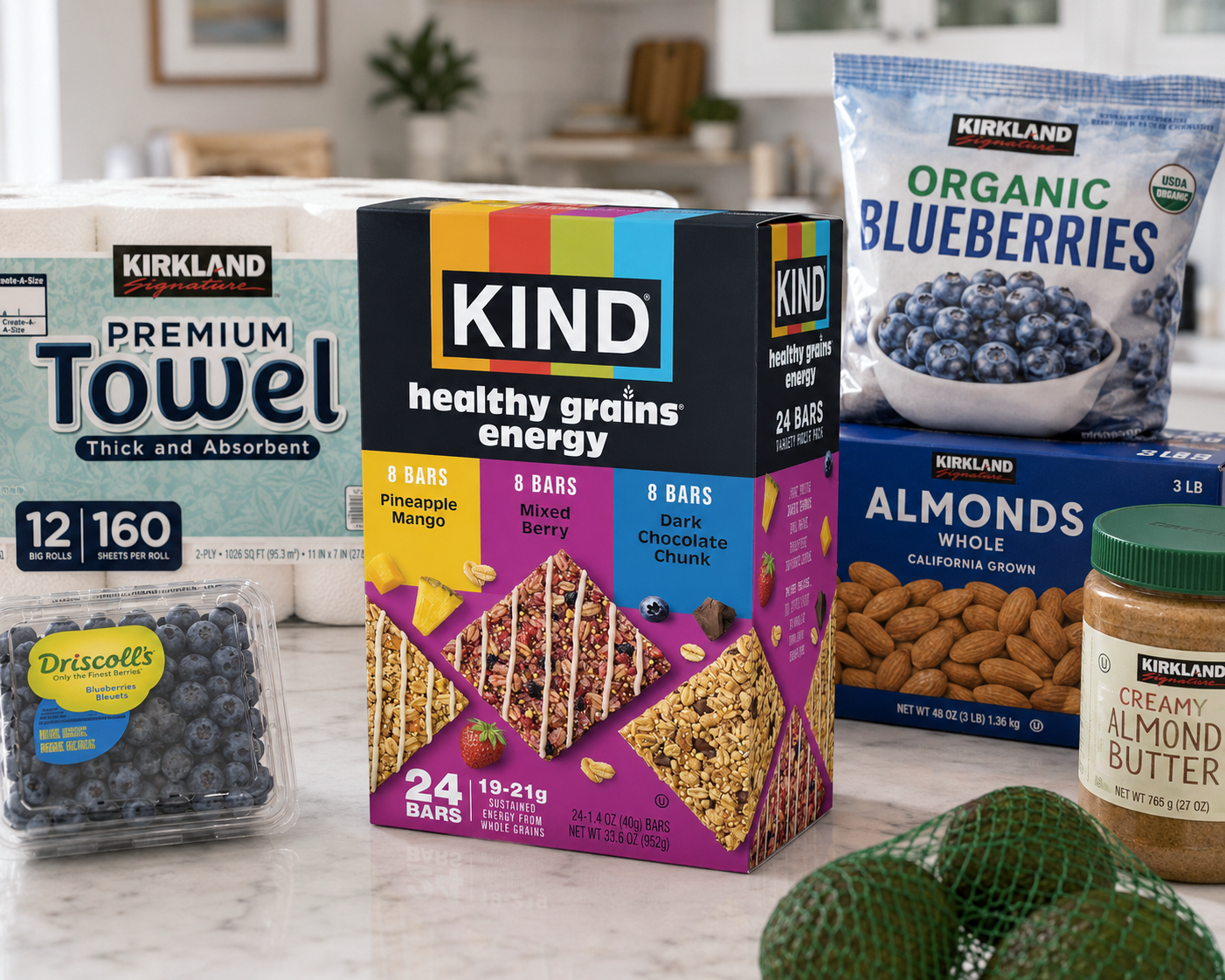 Assorted grocery items including packages of blueberries, almonds, almond butter, a box of KIND healthy grain energy bars, a pack of Kirkland premium towels, and a bag of organic blueberries on a kitchen countertop.