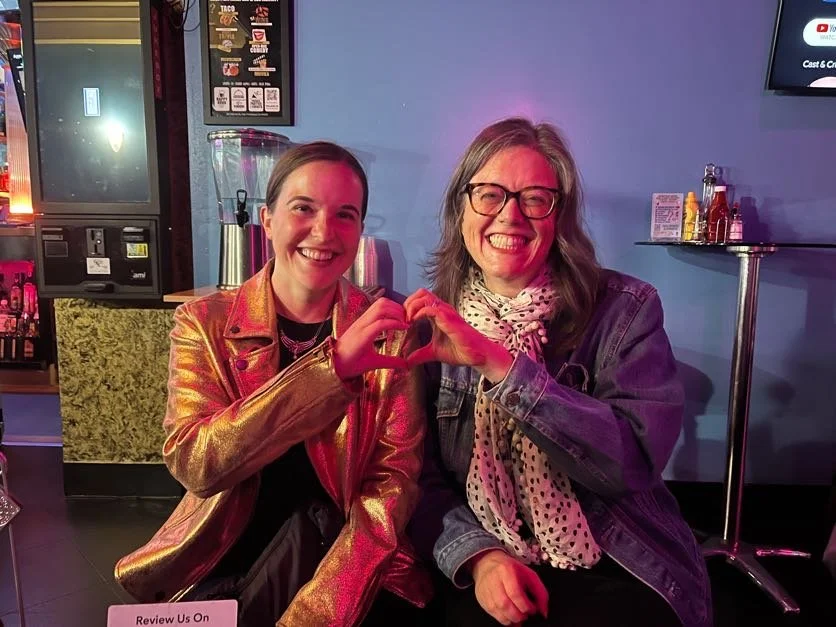 Cadence for Change members sitting together in a restaurant, smiling and forming a heart shape with their hands.