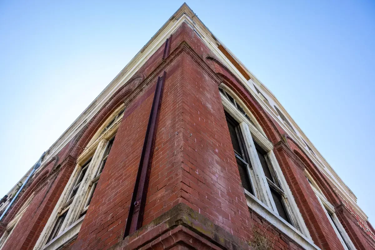 Close-up of an old red brick building, the Fillmore Substation, corner with windows, seen from below against a clear blue sky.