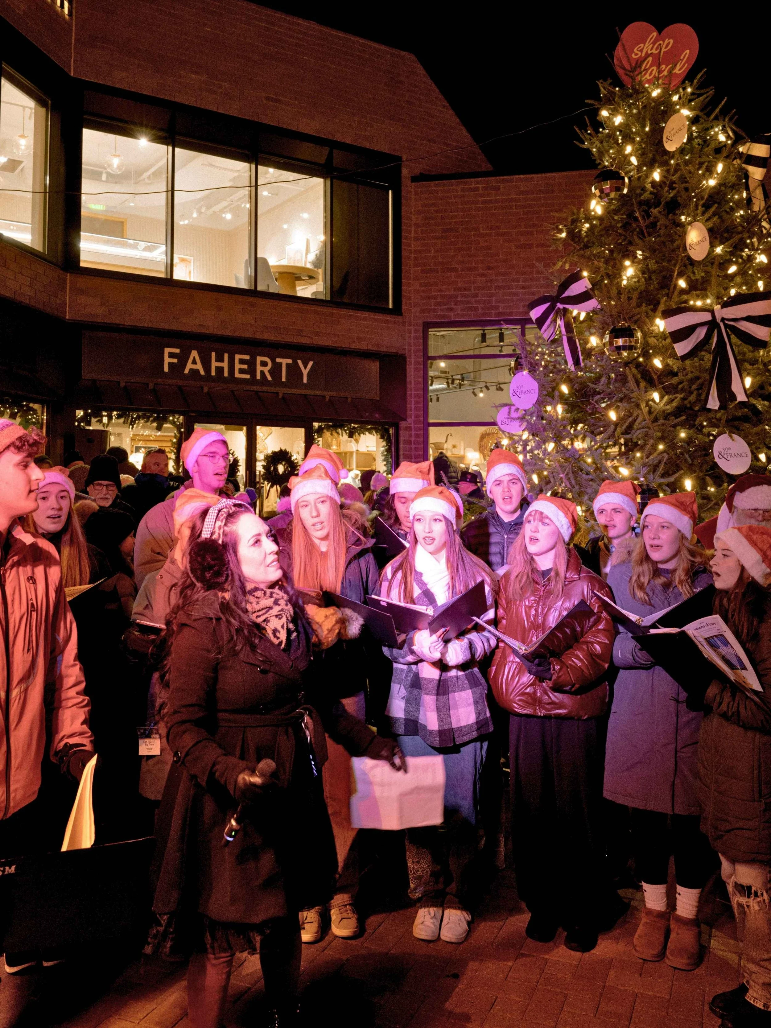 Carolers by the holiday tree at 50th and France