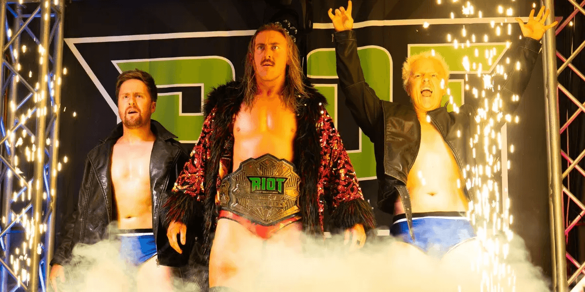 The Armstrongs and Matt Hayter in wrestling gear on a stage with smoke and sparks.