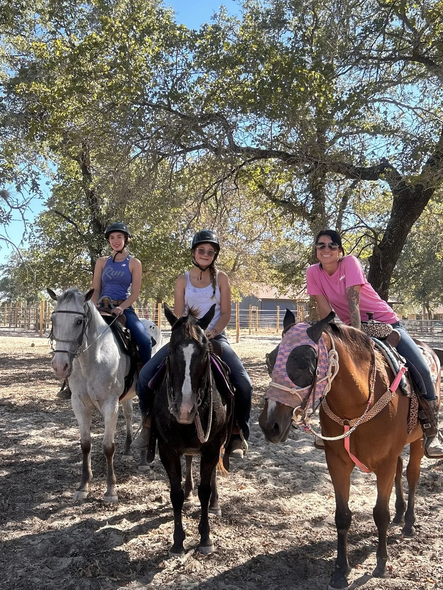 Three riders on horseback smiling at The Gentle Cowgirl in Stockdale, TX — group western riding lessons and trail rides for all ages near San Antonio