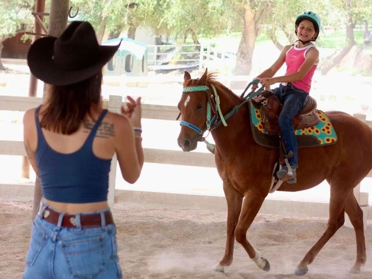Instructor coaching a smiling young girl during a private riding lesson at The Gentle Cowgirl in Stockdale, TX — confidence-building horseback riding lessons for kids near San Antonio