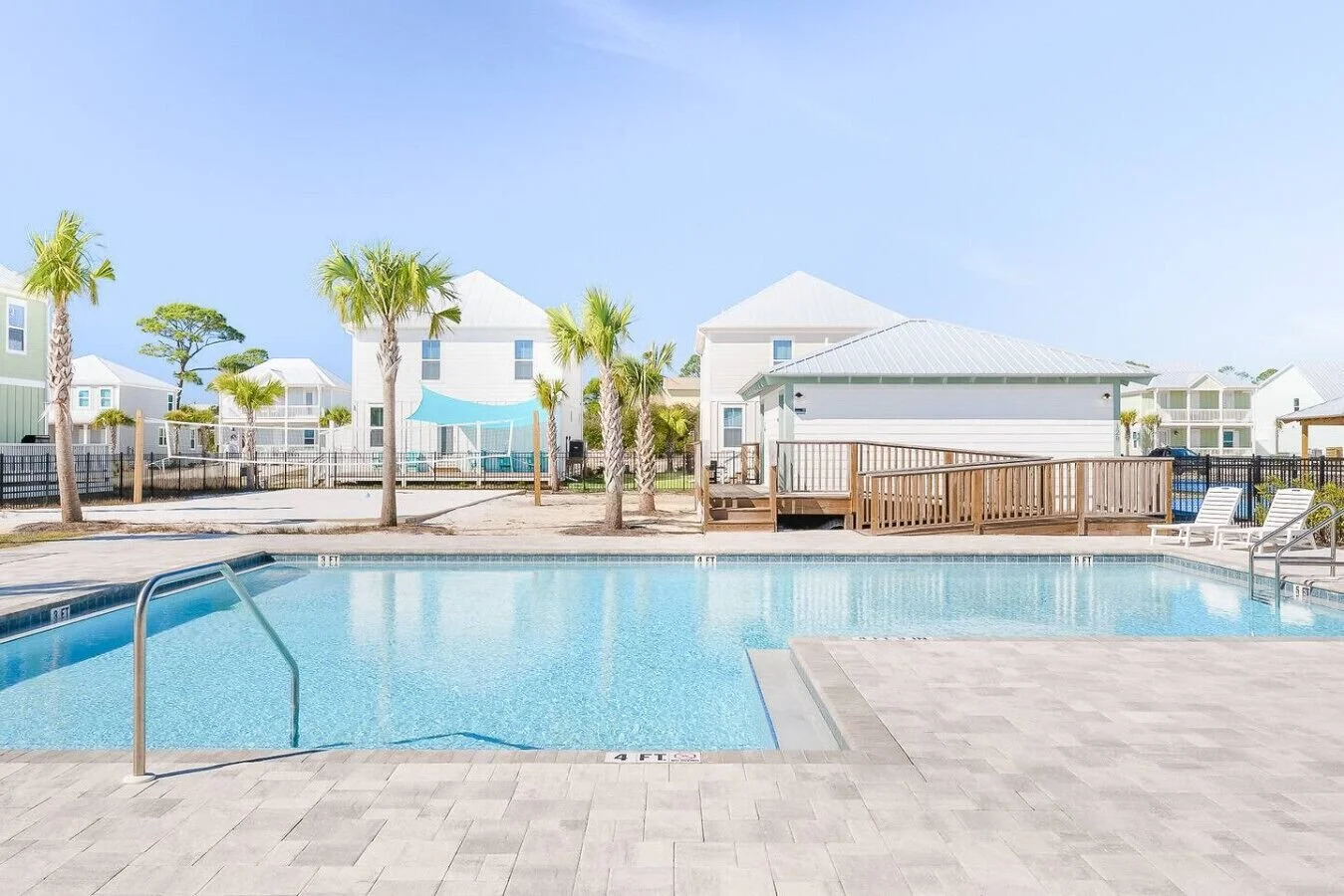 Swimming pool with lounge chairs and palm trees in a sunny residential area Villa Del Sol Cape San Blas, FL