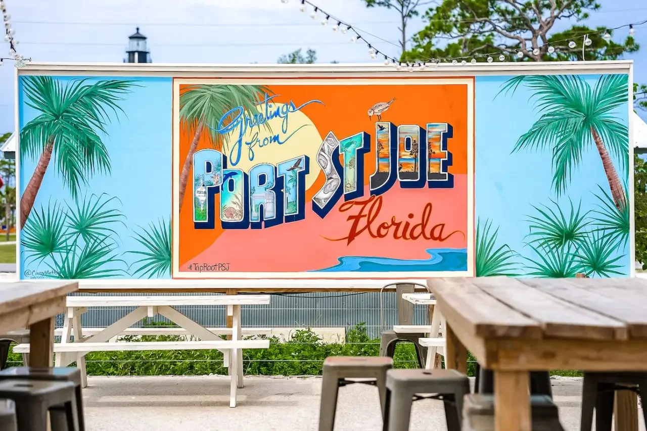 Colorful mural reading "Greetings from Port St. Joe Florida" with palm trees and a scenic background.