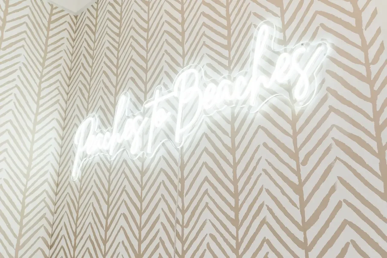 Neon sign on patterned wall that says 'good vibes'.