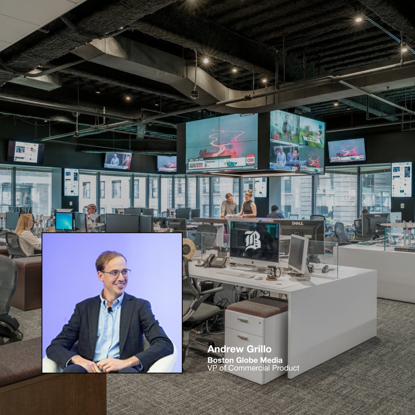 An office environment with multiple workstations, large television screens mounted on the ceiling, and several people working or talking. A separate inset image of a man in a suit smiling, with text indicating his name as Andrew Grillo, Boston Globe Media VP of Commercial Product.