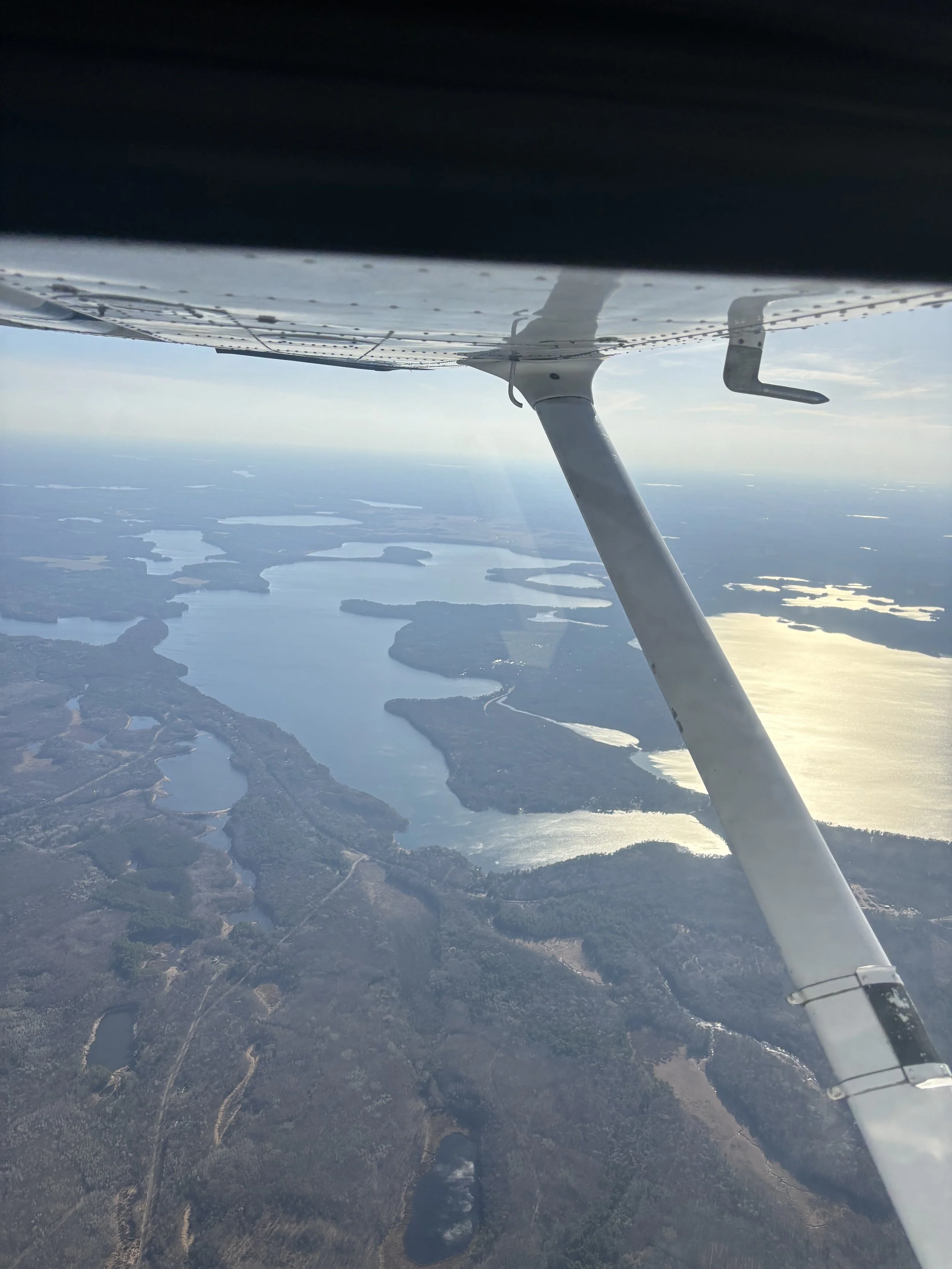 Aerial view of lakes and waterways with surrounding landscape seen from a small aircraft in flight.