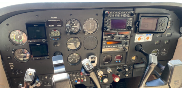 Aircraft cockpit instrument panel with gauges, radios, and controls.