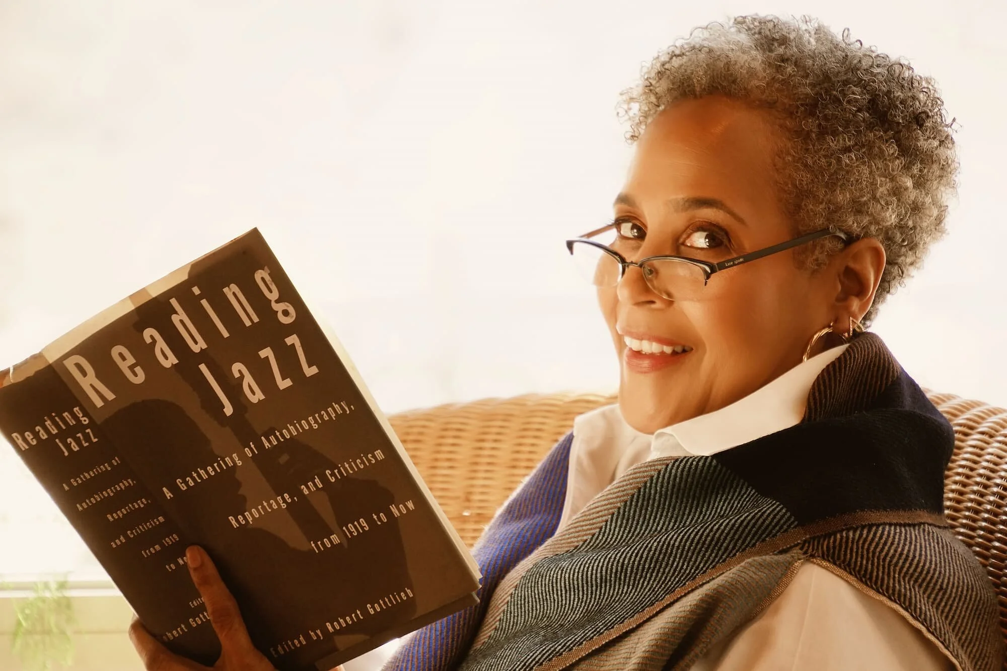Courtney Burton smiling at the camera while reading a book