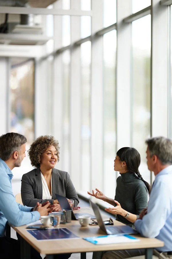 Woman in grey suitcoat leading team meeting