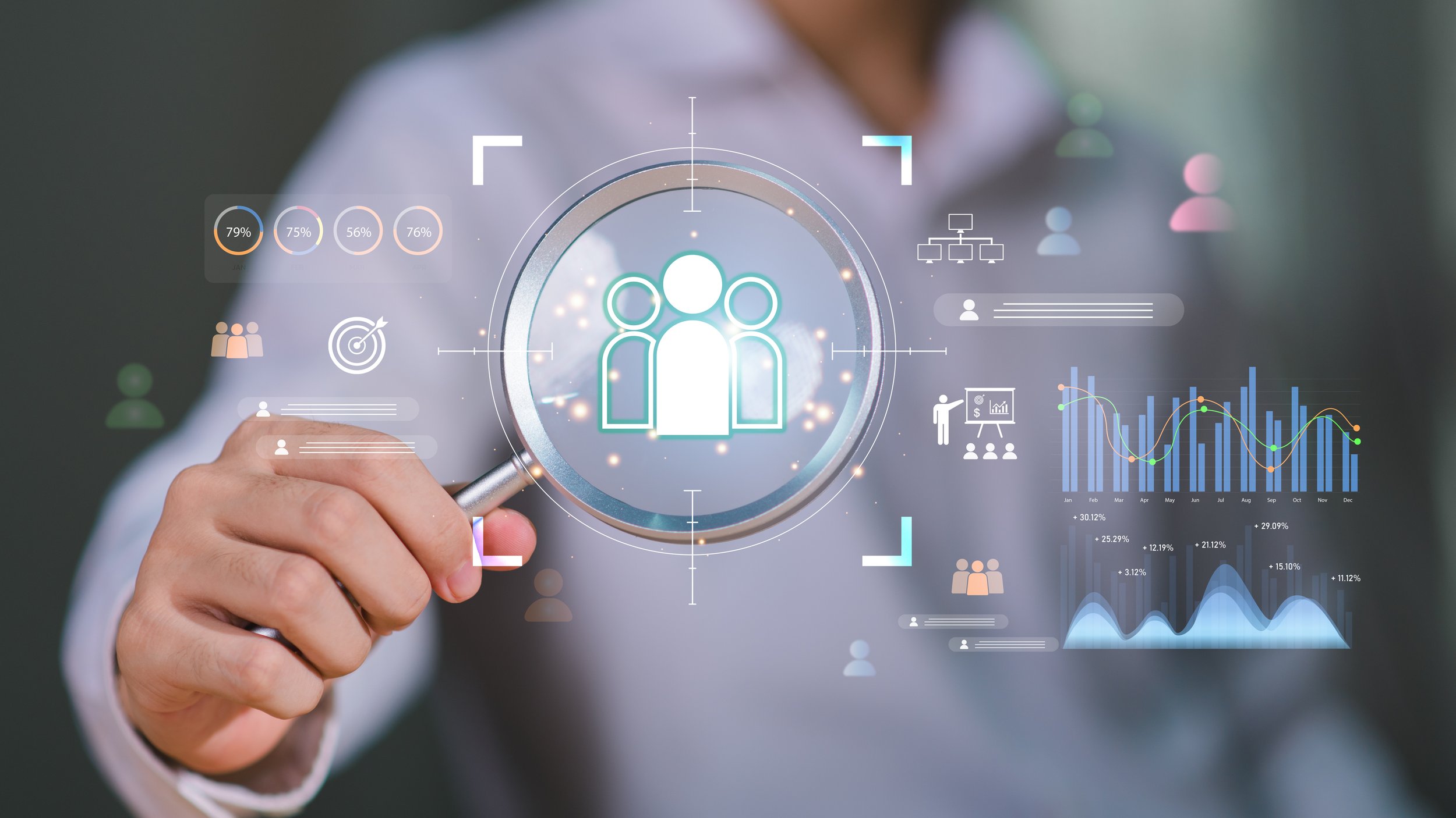 Person holding magnifying glass over digital interface with icons of people, graphs, and organizational charts.