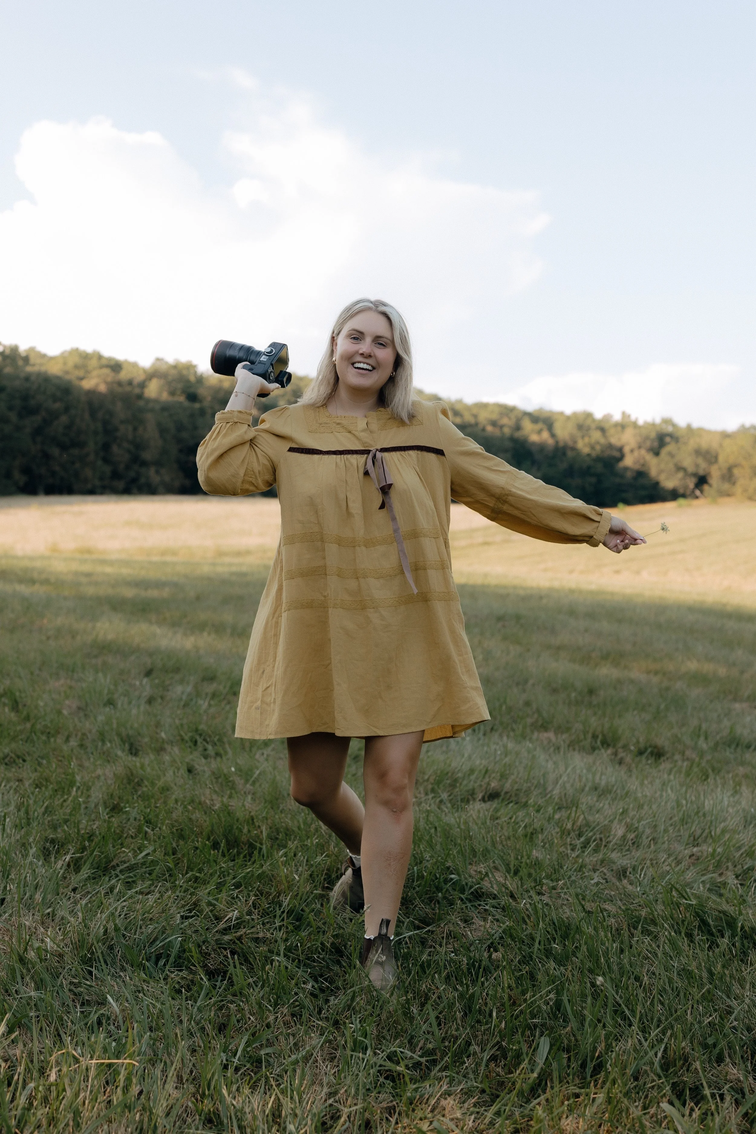 Rachel Kosky, Tennessee wedding photographer, laughing and dancing in a golden hour field with camera in hand and arms outstretched — R Photos, Chattanooga TN