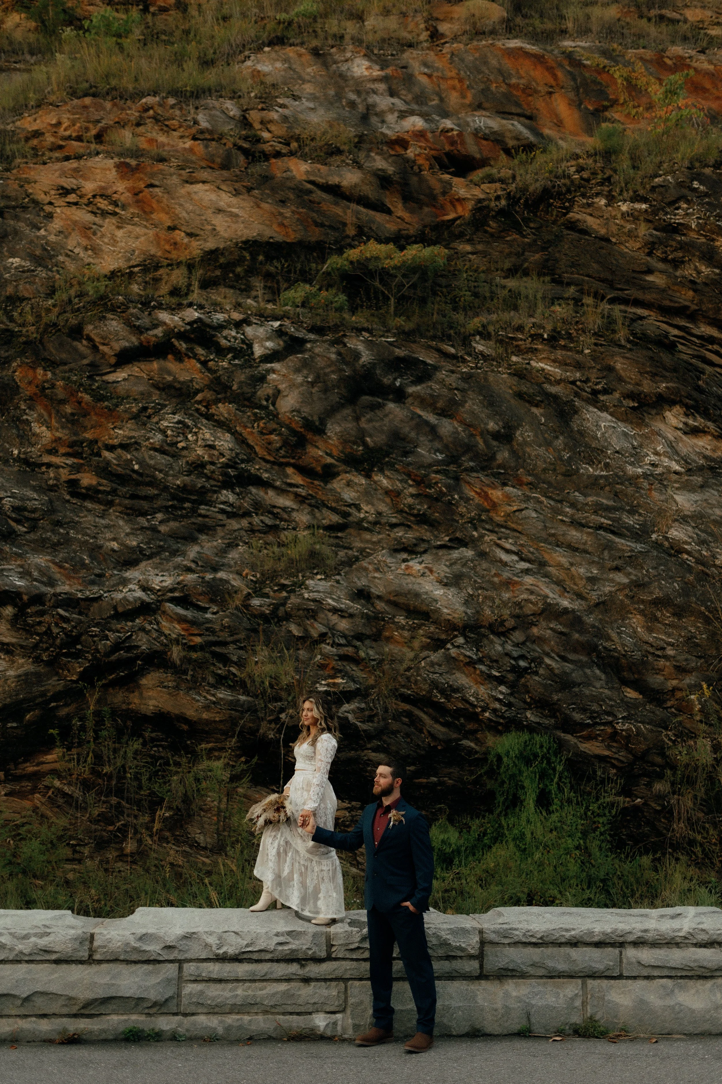 Bride and Groom standing on large rock wall after their intimate western wedding in the smoky mountains - Foothills Parkway Wedding Photographer
