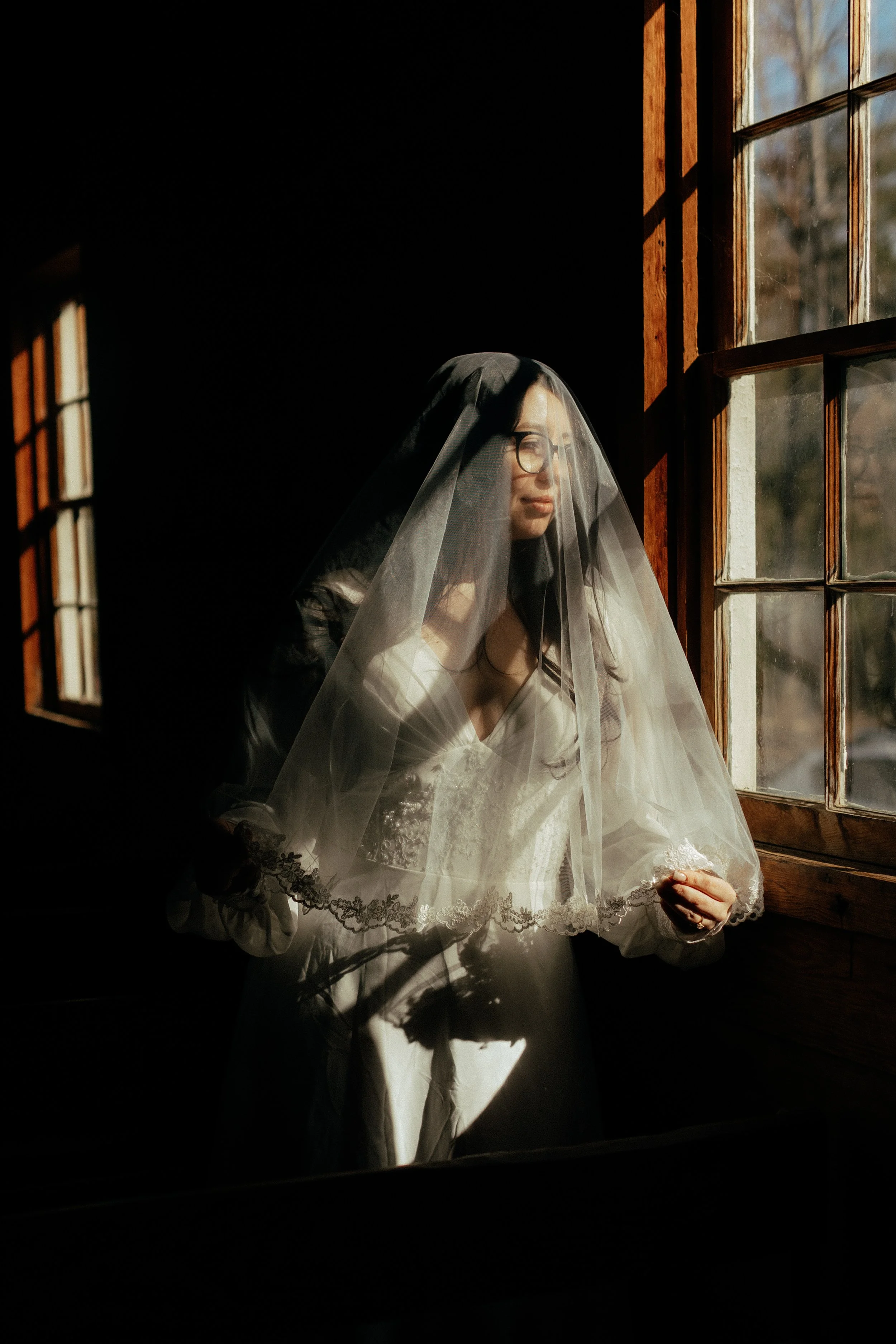 Bride in vintage veil looking out of a church window before a soft gothic wedding ceremony in Nashville Tennessee