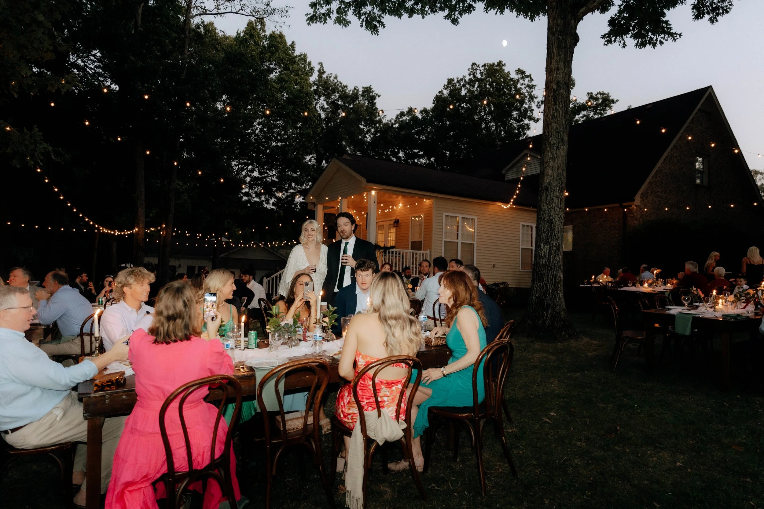 Intimate backyard wedding reception at dusk with string lights and candlelit tables near Nashville, TN.