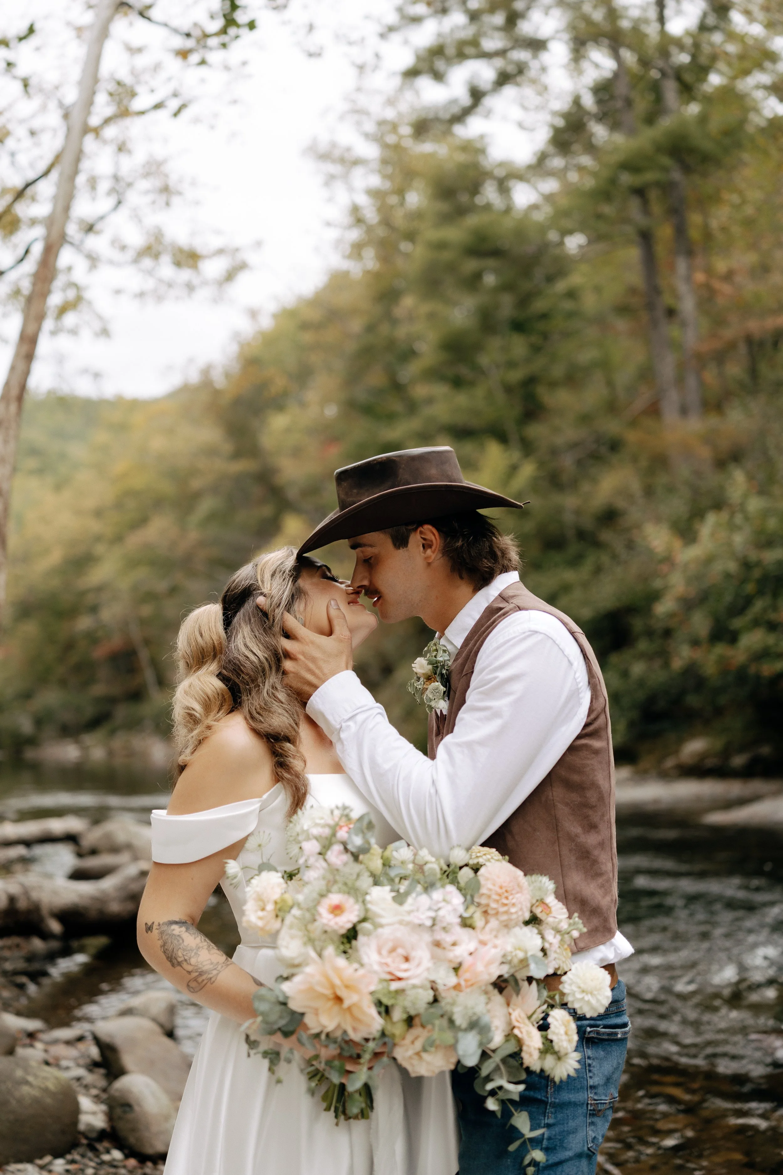Bride and Goom about to kiss riverside in the smoky mountains after their intimate ceremony with fresh local flowers bouquet - smoky mountain elopement photographer.