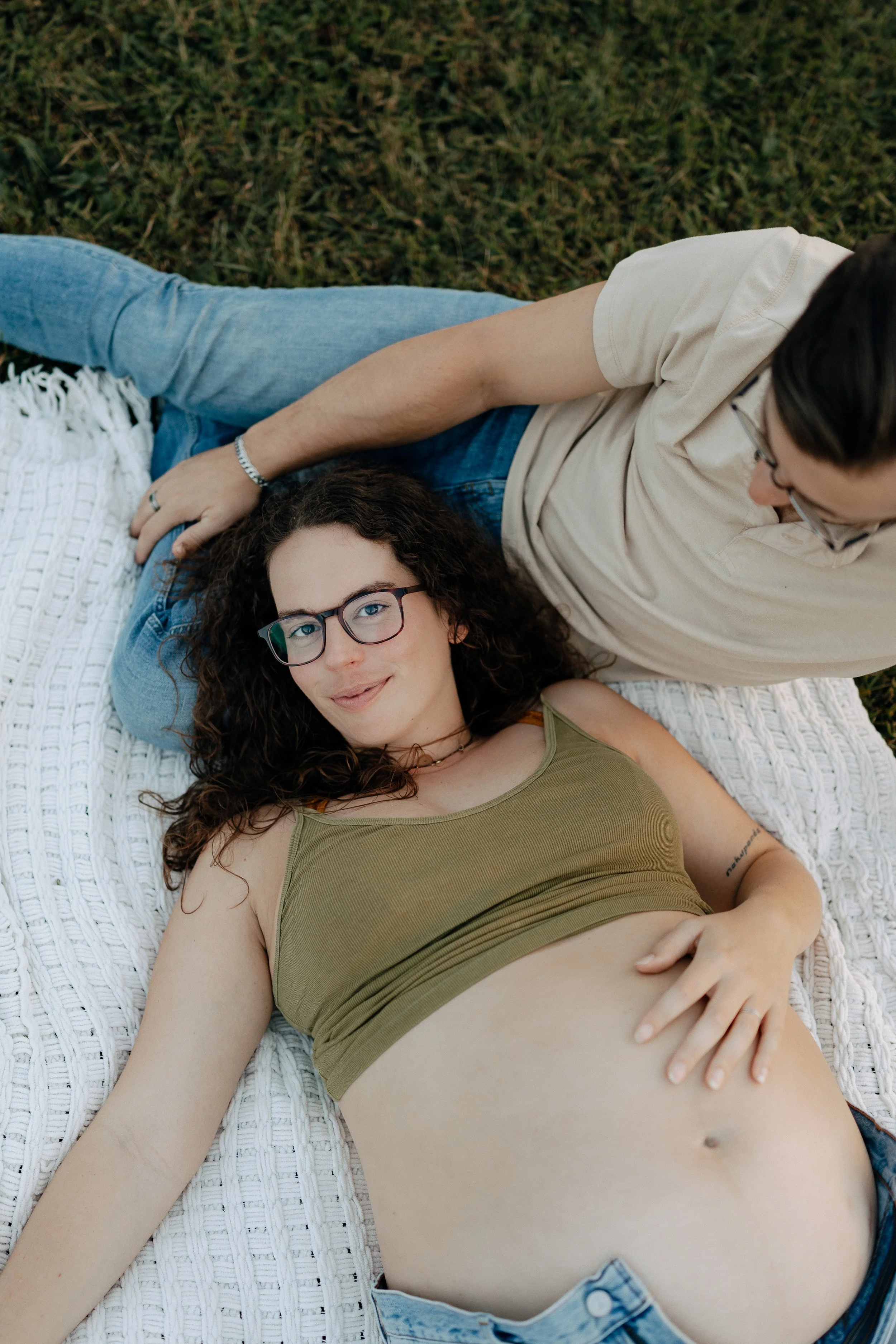 Relaxed Pregnant women laying on father in blue jeans at sunset - Maryville Luxury Maternity Photography