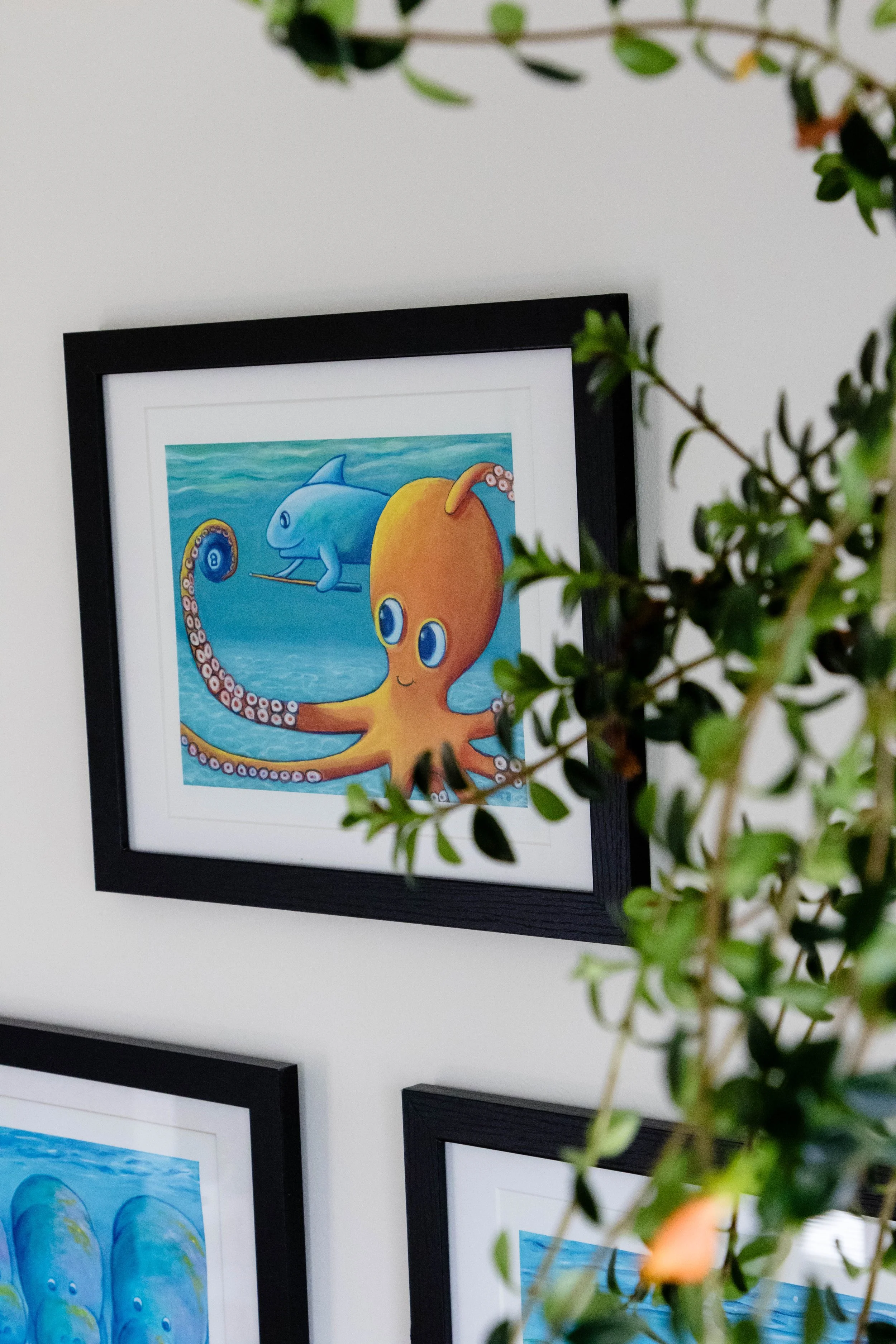 Framed illustration of an octopus with a cheerful expression, holding a fishing pole with a net, underwater scene with a dolphin in the background, and a blue sky.