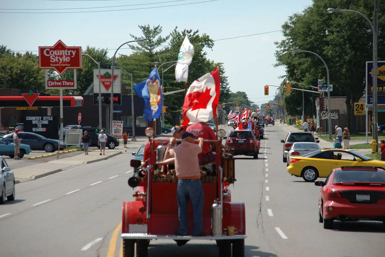Classic cars and antique fire trucks cruising down a main street in Wallaceburg with onlookers for the annual Terry Glover Memorial Cruise