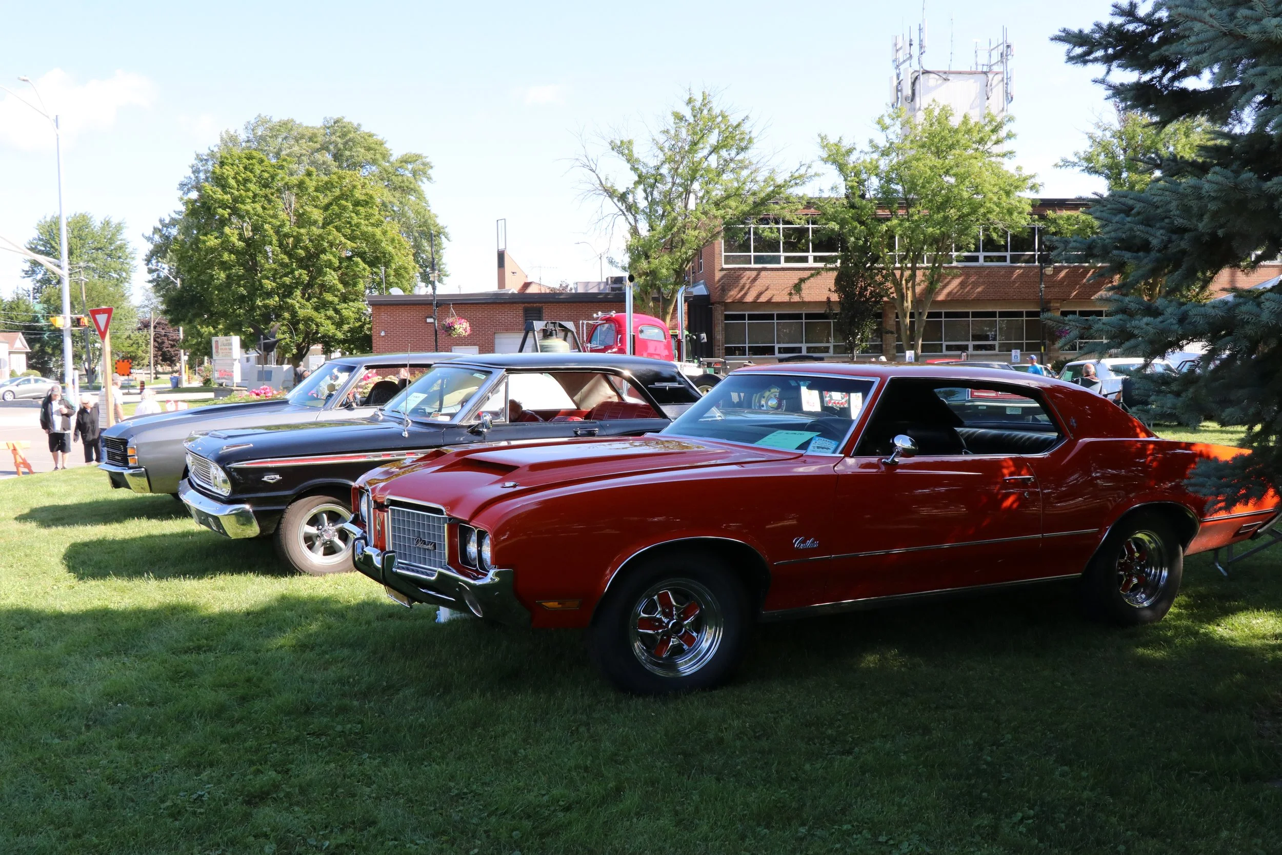 Three classic cars lined up on the grass in Civic Square Park in Wallaceburg for WAMBO